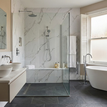 Modern bathroom with carara white pvc wall panels, a freestanding bathtub, and a glass shower enclosure.